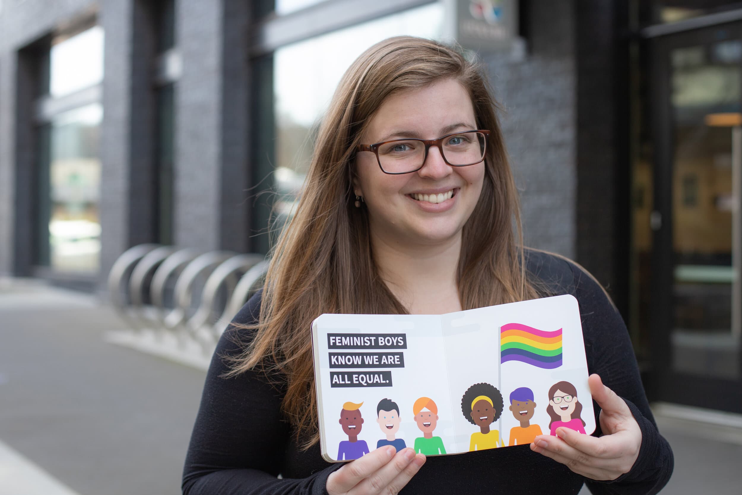 Elizabeth Rhodes holding her book Feminism is for Boys at a speaking event